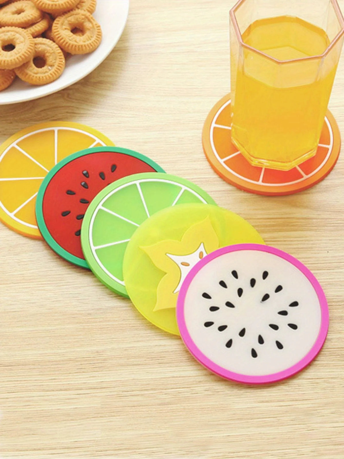 A set of colorful fruit pattern PVC coasters, including orange, watermelon, lime green, and pink slices, are displayed on a w