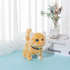 An orange fluffy plush cat toy standing on a light blue surface next to a vase of dried flowers.