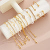 A collection of 11 gold-toned bracelets featuring crystal hearts, infinity signs, and various bead styles displayed on a ligh