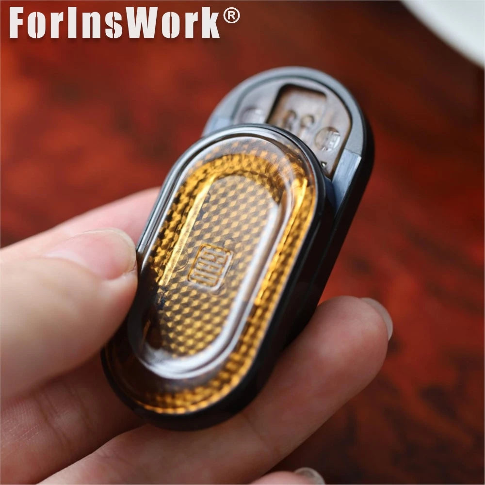 A hand holds a black metal mechanical fidget slider with an amber gem design.