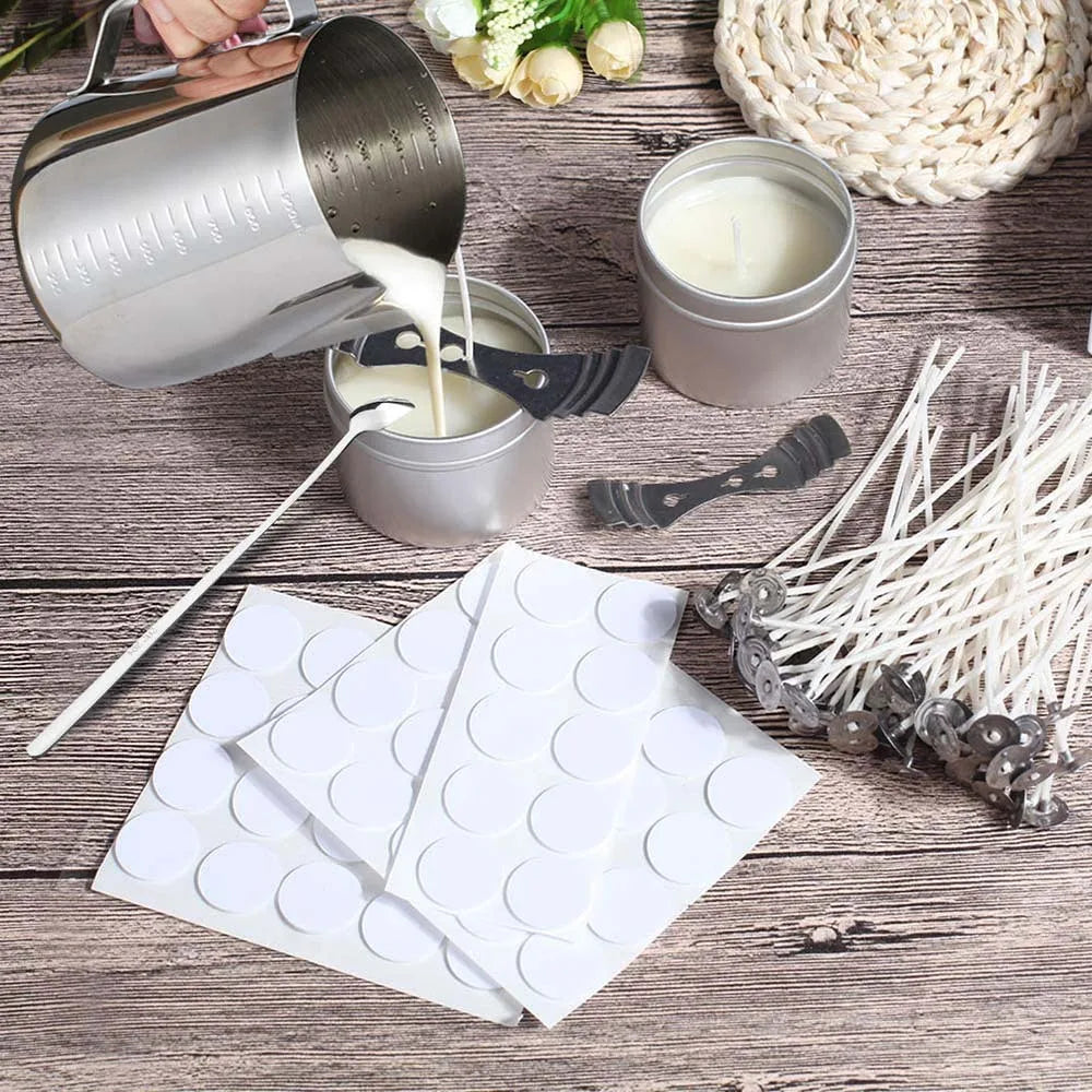 A close-up of pre-waxed cotton candle wicks with metal sustainers and a metal pouring vessel on a wooden surface.