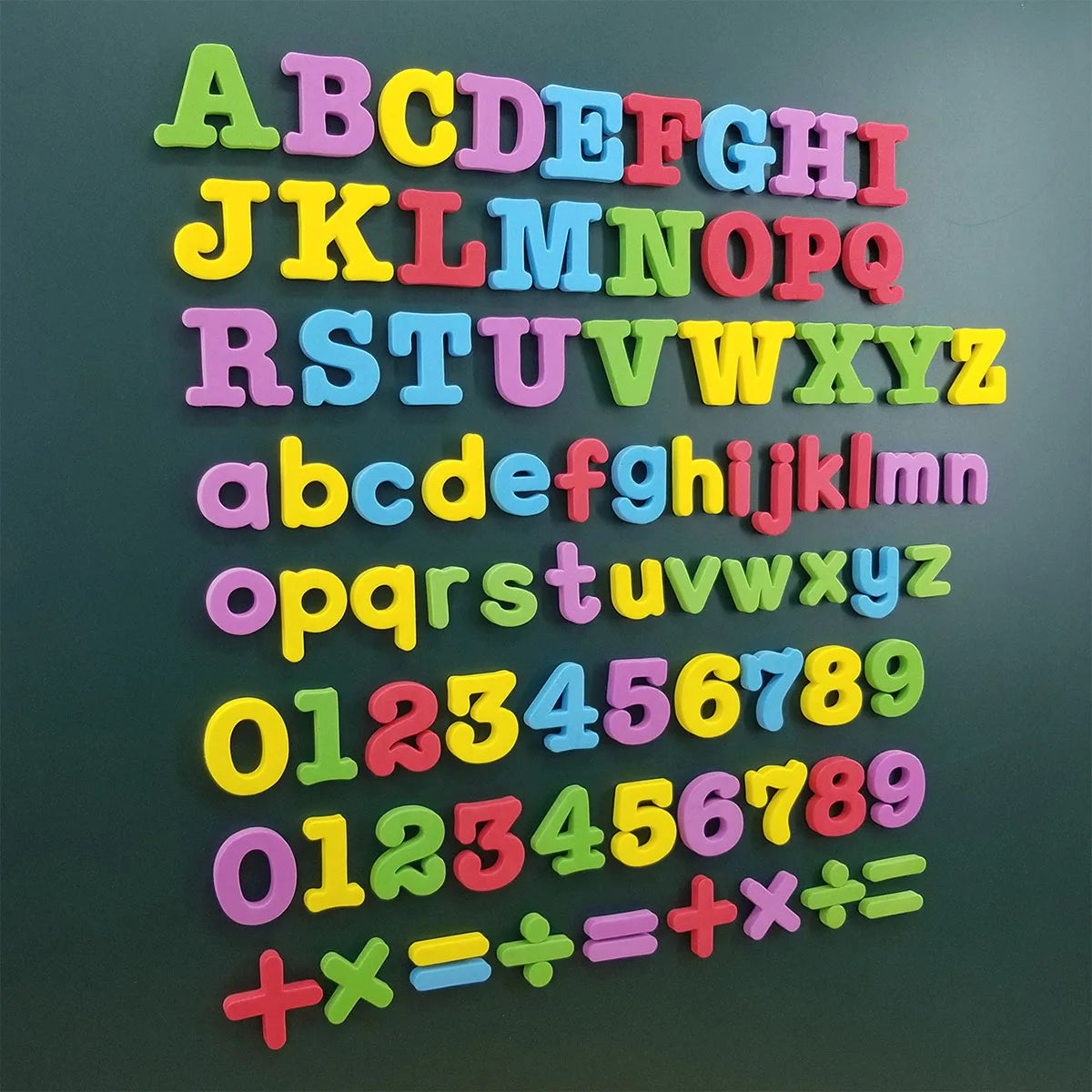 Una colección de letras y números magnéticos de colores, dispuestas en filas sobre una superficie verde oscura.