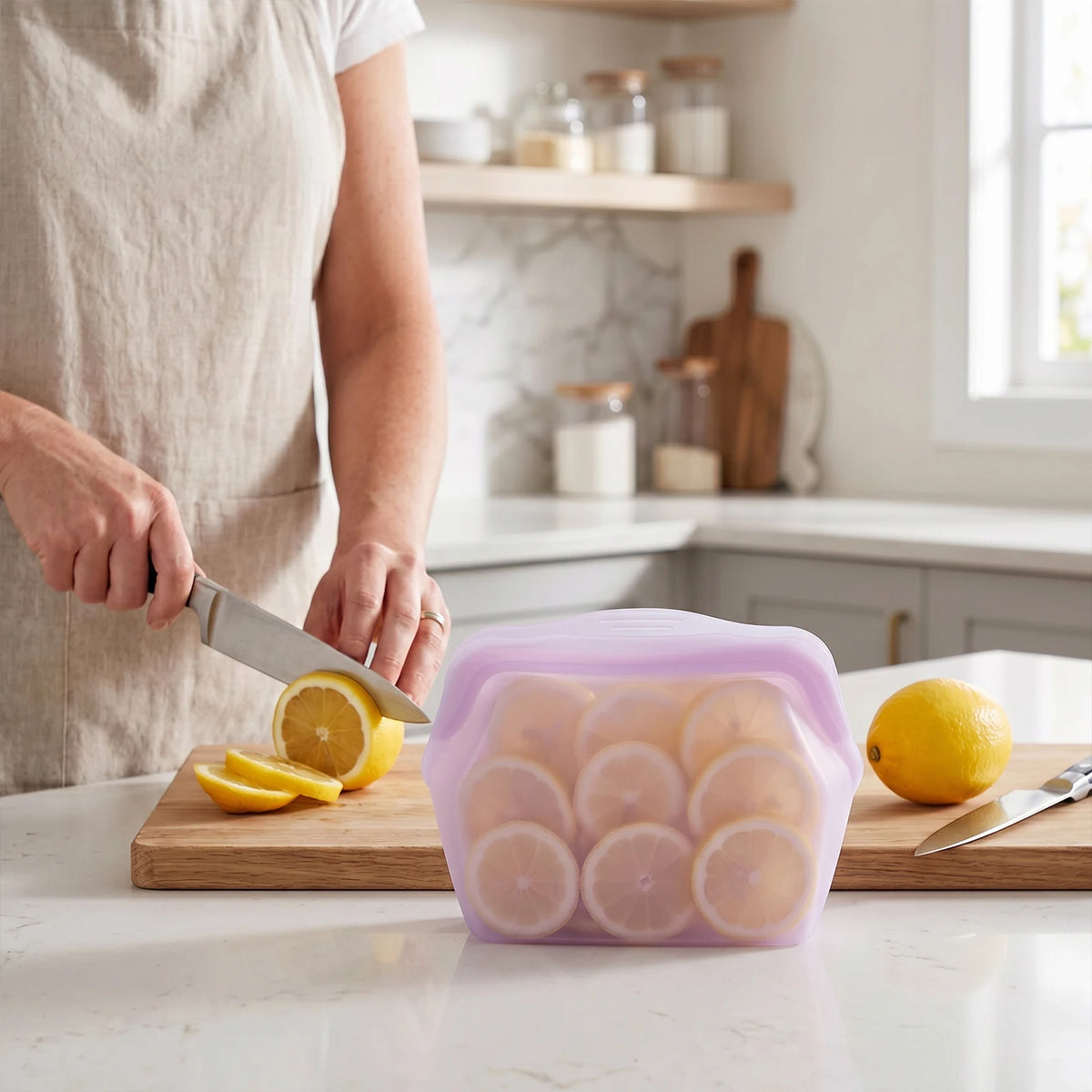 Reusable silicone storage bags filled with sliced lemons on a wooden cutting board.