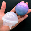 A hand holds a purple and blue iridescent sphere and a clear silicone mold for resin crafting.