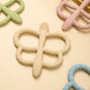 A collection of soft silicone butterfly teethers in various pastel colors, including green, pink, and light beige.