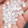 A hand holds a pile of clear acrylic alphabet beads for jewelry making