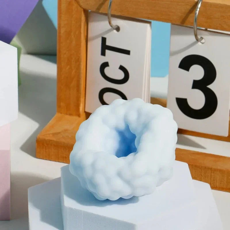 A light blue, squishy stress relief ball is displayed in front of a wooden frame with month and day tags.