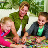 Two people are assembling a wooden big cat jigsaw puzzle on a table.