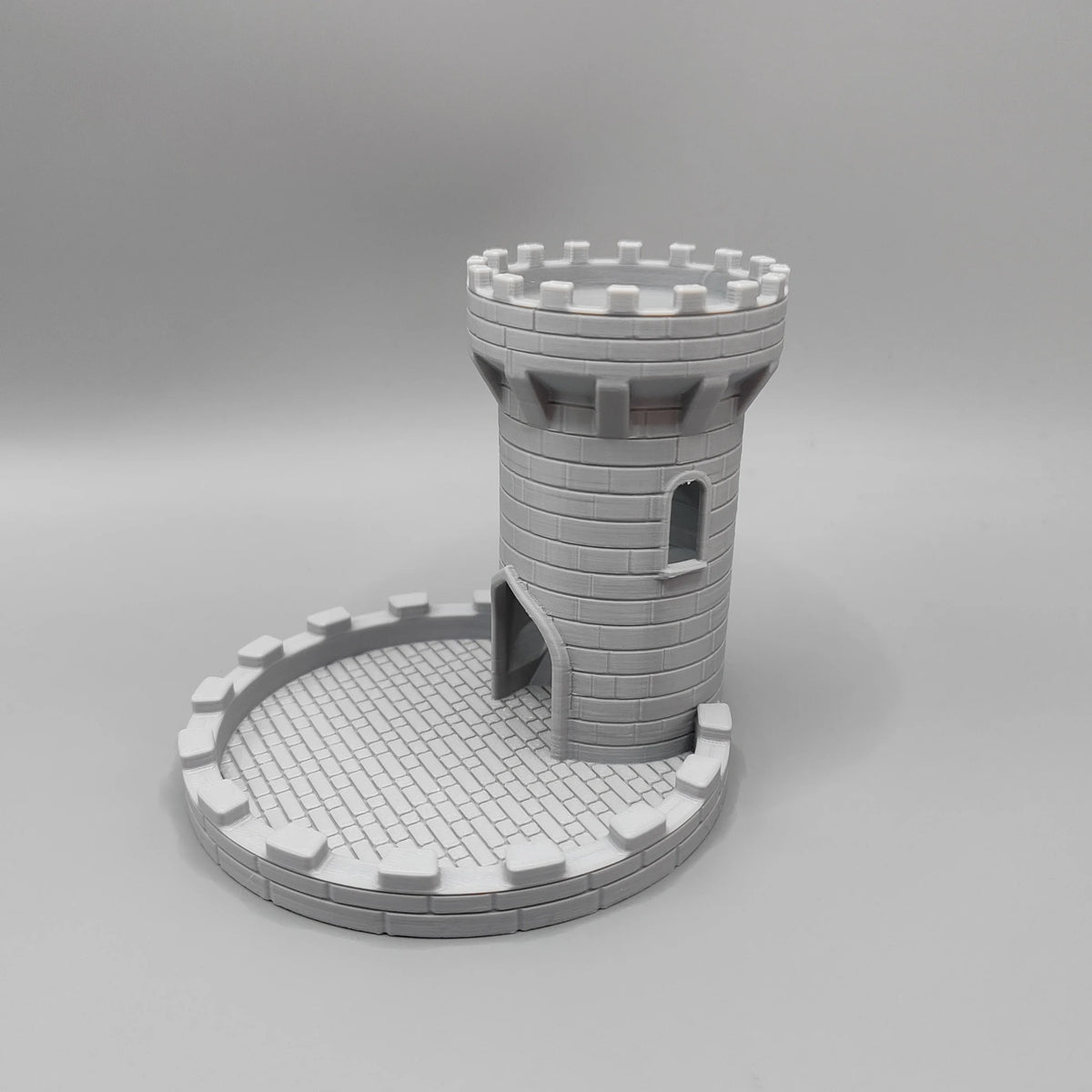 A gray LEGO model of a medieval castle tower with crenellations and an attached tray for tabletop games.