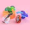 A green and yellow dinosaur egg toy is displayed next to a white and black dinosaur figure on an orange stand.
