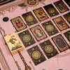 A spread of mini gold foil tarot cards laid out on pink parchment with a golden quill.