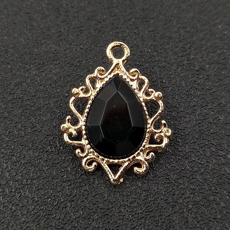 Gold plated water droplet charm featuring a black crystal and an ornate flower design.
