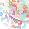 A collection of colorful glass butterfly beads in various shades of pink, green, blue, and orange scattered on a white plate.