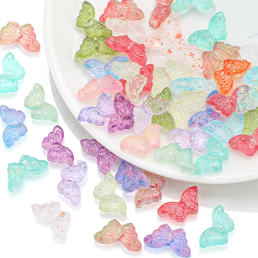 A collection of colorful glass butterfly beads in various shades of pink, green, blue, and orange scattered on a white plate.