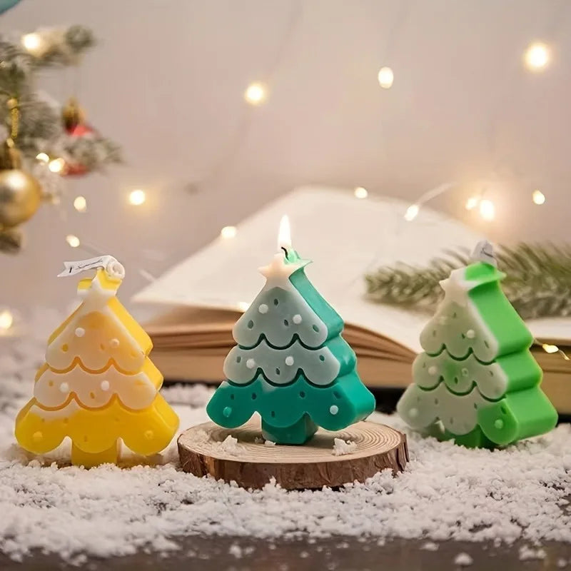 A silicone Christmas tree shaped candle mold with a green and white design sits on a wooden slice covered in snow.