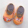 Pair of orange baby barefoot water shoes with light brown straps