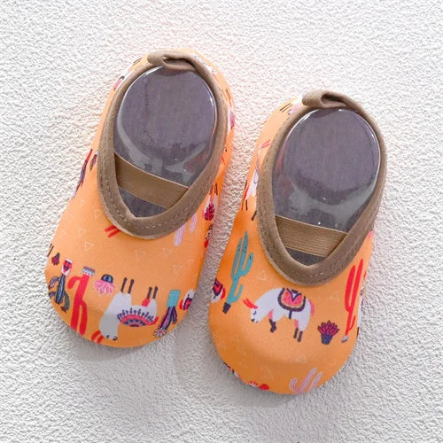 Pair of orange baby barefoot water shoes with light brown straps