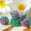 A set of seven resin polyhedral dice with a display frame resting on a light surface next to white flowers.