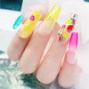 A hand holds several polymer clay flower charms in various bright colors and designs for DIY crafts.