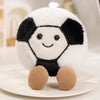 A white and black plush doll resembling a cow face with brown feet sitting on a light surface.