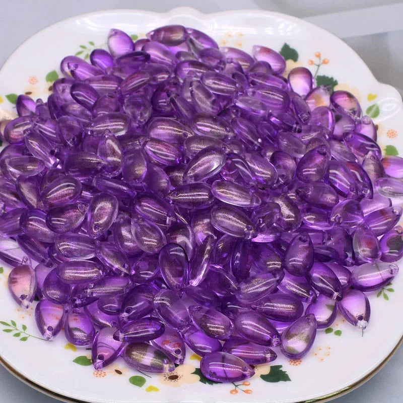 A pile of purple water drop Czech glass beads for jewelry making displayed on a white plate.