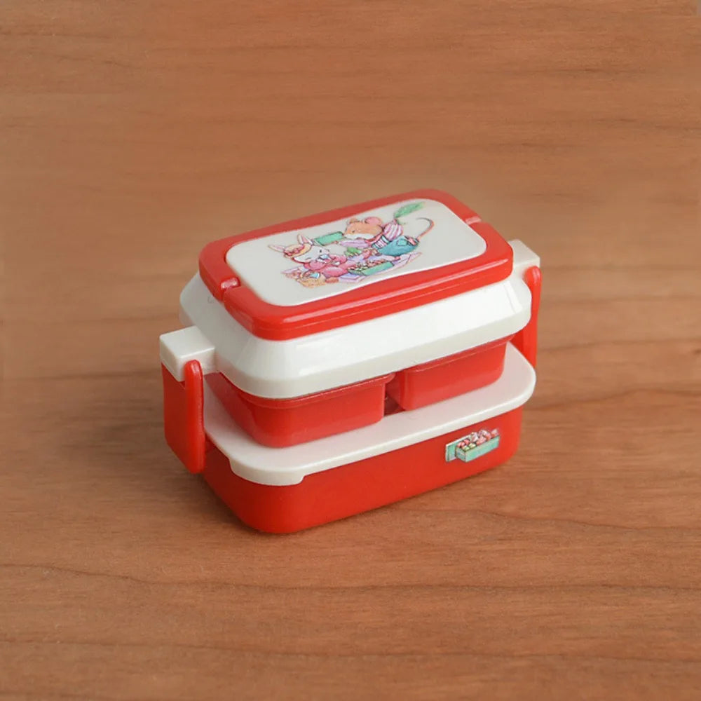 A miniature doll picnic lunch box with a red and white design sits on a wooden surface.
