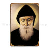 A vintage metal wall sign featuring a portrait of Saint Charbel with a beard against a dark background.