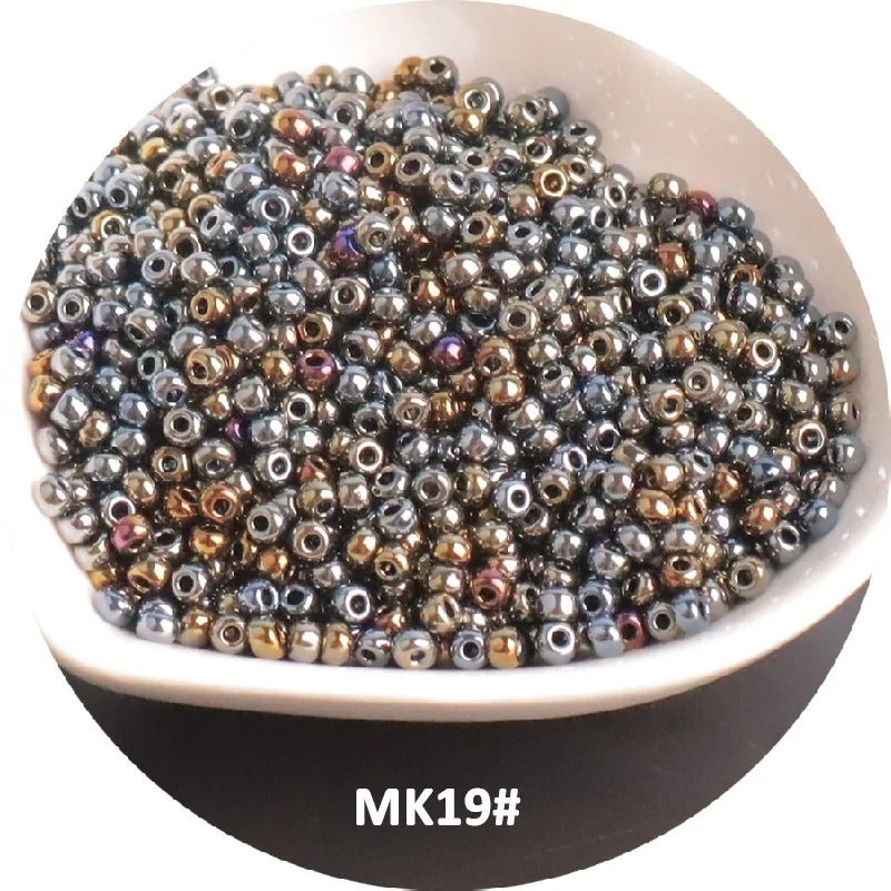 A pile of small, iridescent metallic glass beads in various shades of bronze and silver on a white dish.