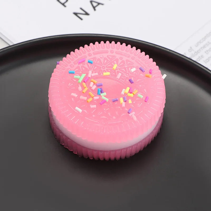 A pink squishy stress relief toy with colorful sprinkles resting on a dark gray surface.