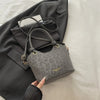 A gray floral canvas tote bag with leather straps is shown resting on a dark gray blazer.