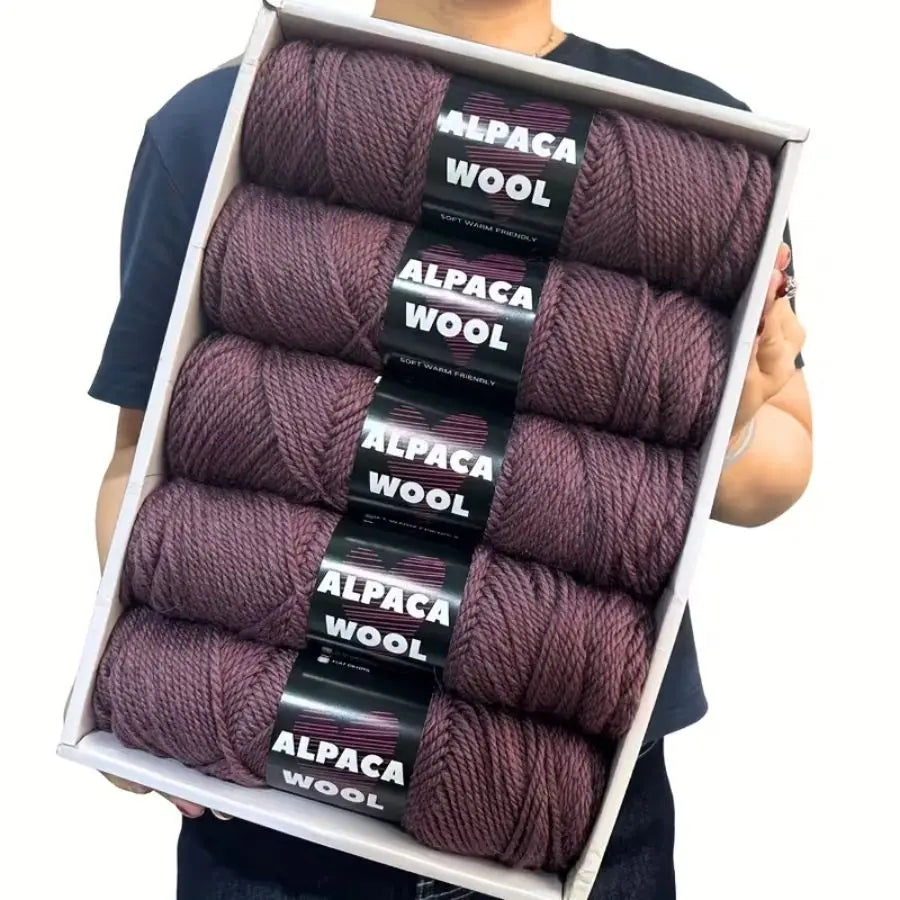 A box displaying five skeins of purple alpaca wool yarn for knitting and crochet projects.