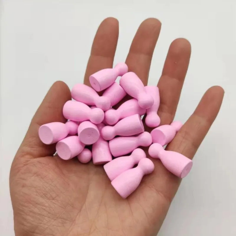 A hand holds a set of ten pink wooden chess pawns for board games.