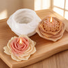 A silicone candle mold featuring a pink rose design is placed on a wooden board next to a lit candle.
