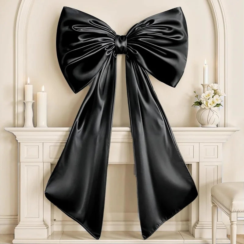 A large black satin bow decoration displayed on a white mantelpiece with candles and flowers.
