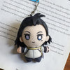 A plushie pendant charm of an anime character with dark hair and blue eyes is displayed against a piece of paper.