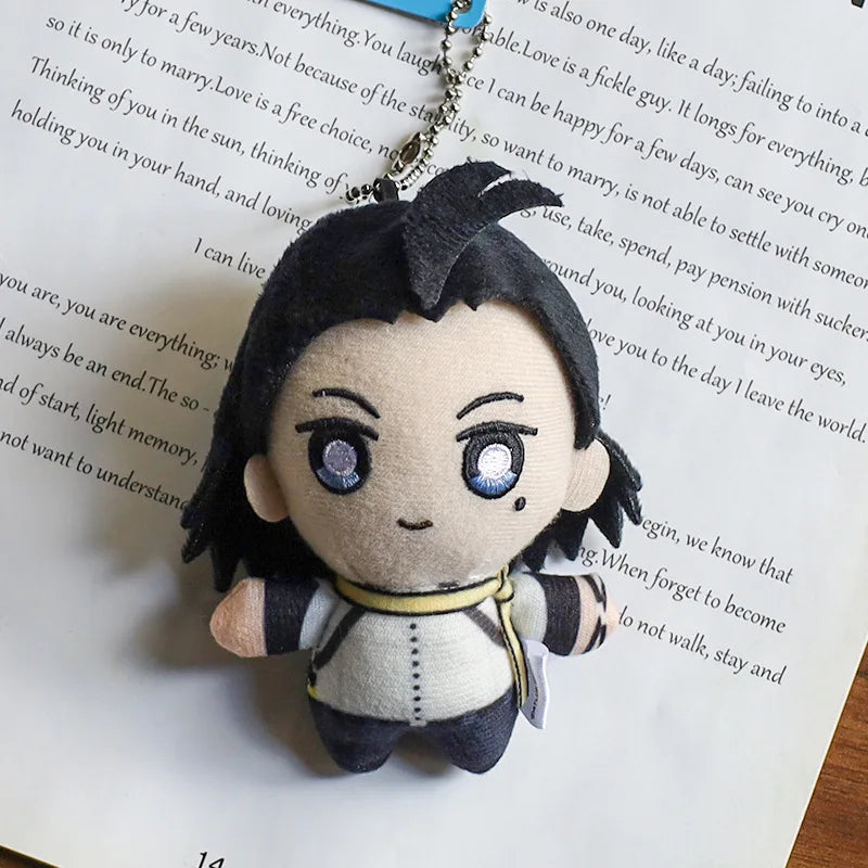 A plushie pendant charm of an anime character with dark hair and blue eyes is displayed against a piece of paper.