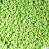 A pile of bright lime green plastic bead filler for DIY squishy toys and stress relief crafts.