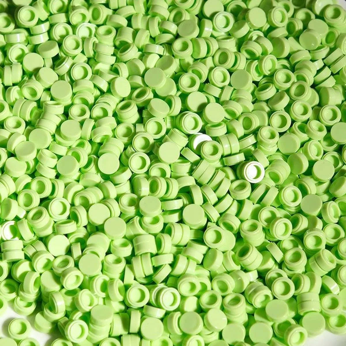 A pile of bright lime green plastic bead filler for DIY squishy toys and stress relief crafts.