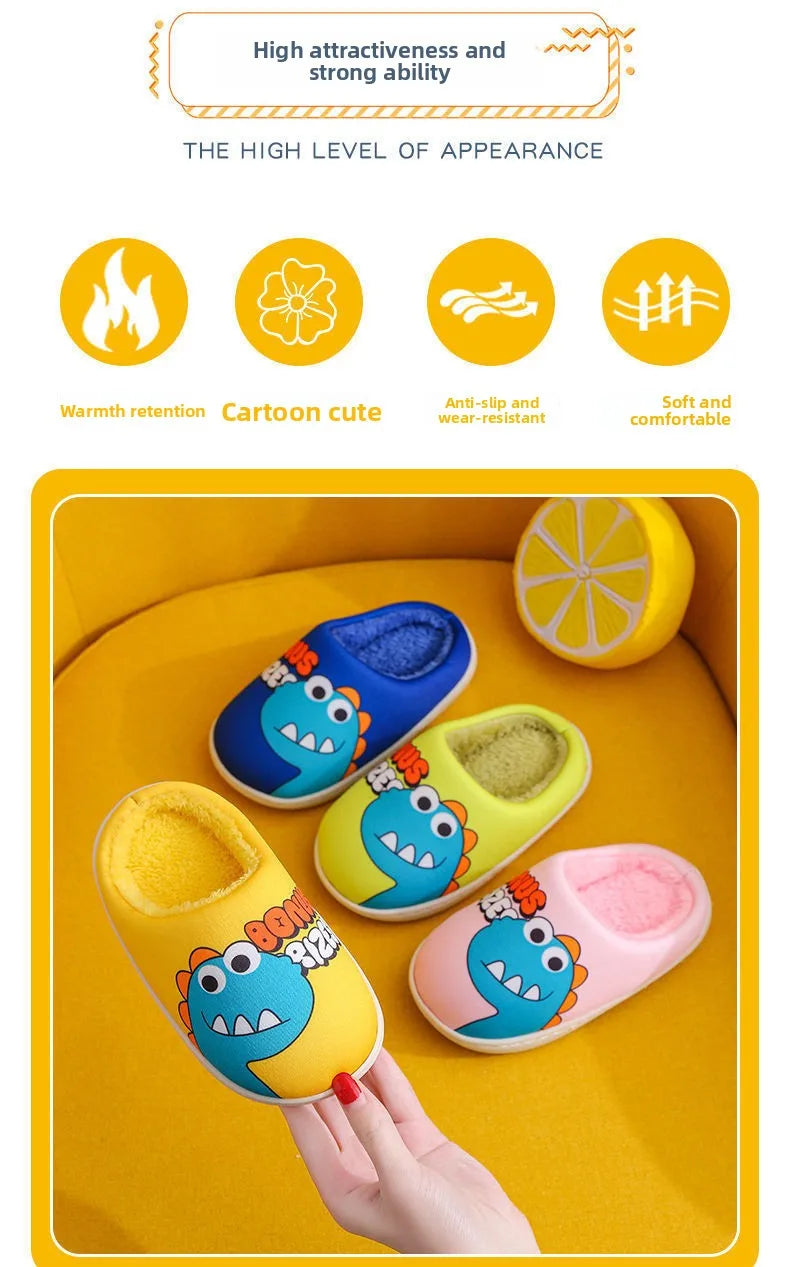 A hand is holding a pair of yellow and blue cartoon dinosaur plush slippers on a yellow surface.