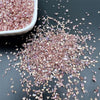 Crushed pink and purple glass crystals scattered on a dark surface.