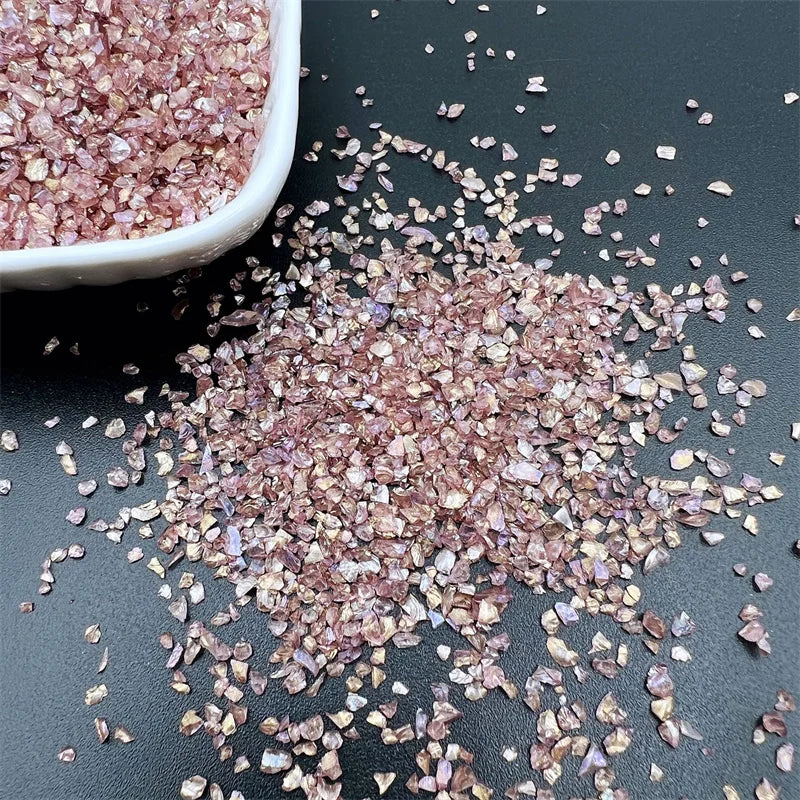 Crushed pink and purple glass crystals scattered on a dark surface.