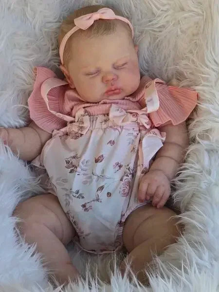 A newborn baby doll with hand-painted skin is lying in a fluffy white fur setting.