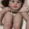 A lifelike reborn baby doll kit featuring a baby with brown hair and blue eyes wearing a pink hooded garment.