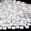 A close-up view of clear and white sparkling crystal flatback rhinestones scattered on a dark surface.