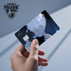 A hand holds up an anime dragon PVC card skin sticker featuring a white-haired male character with blue eyes against a dark, 