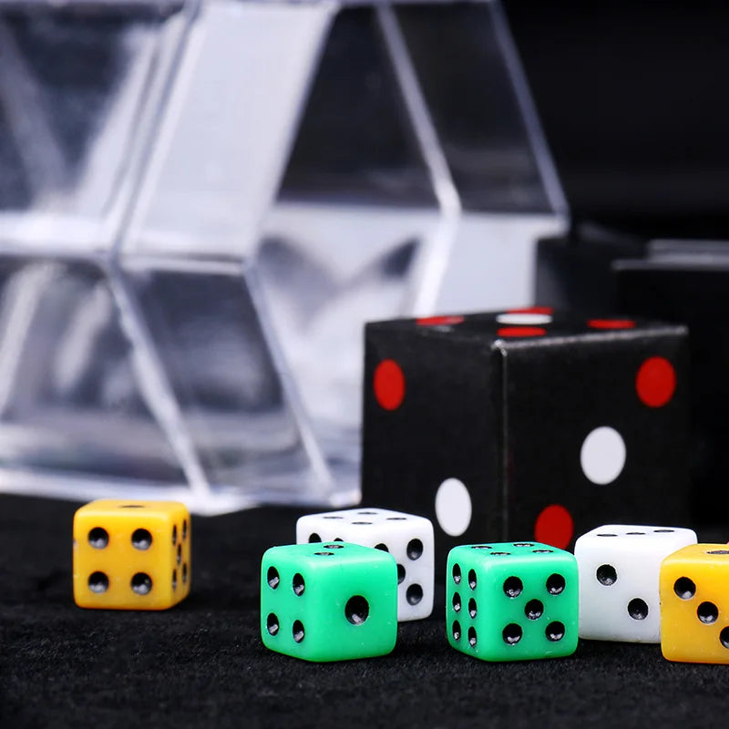 A collection of colorful dice, including yellow, green, and white, are displayed in front of a clear geometric box.