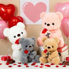 A collection of plush teddy bears, including a white bear, a gray bear, and a pink bear, with red rose petals scattered on th