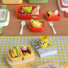 A collection of miniature doll picnic lunch boxes in yellow and red, some filled with food items like fruit and sandwiches.