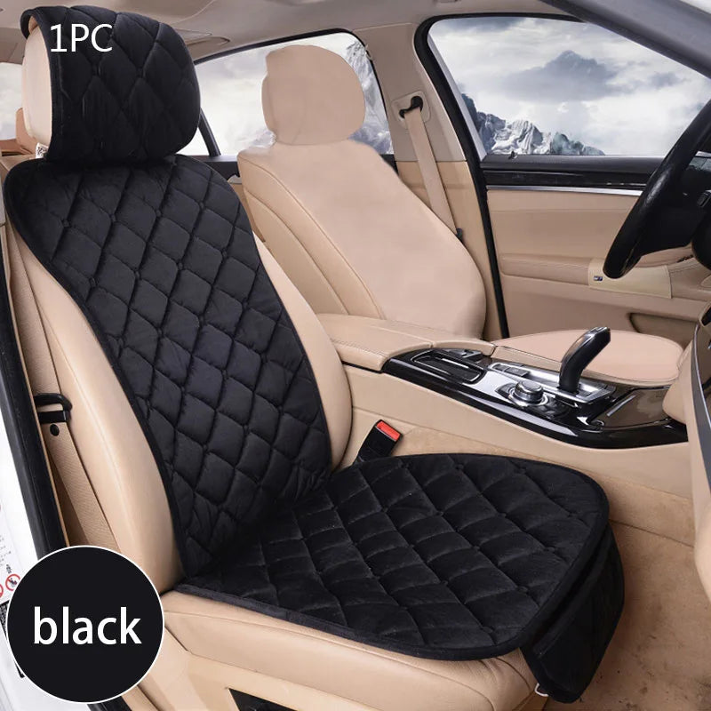 A black universal car seat protector with a quilted pattern is shown installed in the passenger seat of a light beige car.