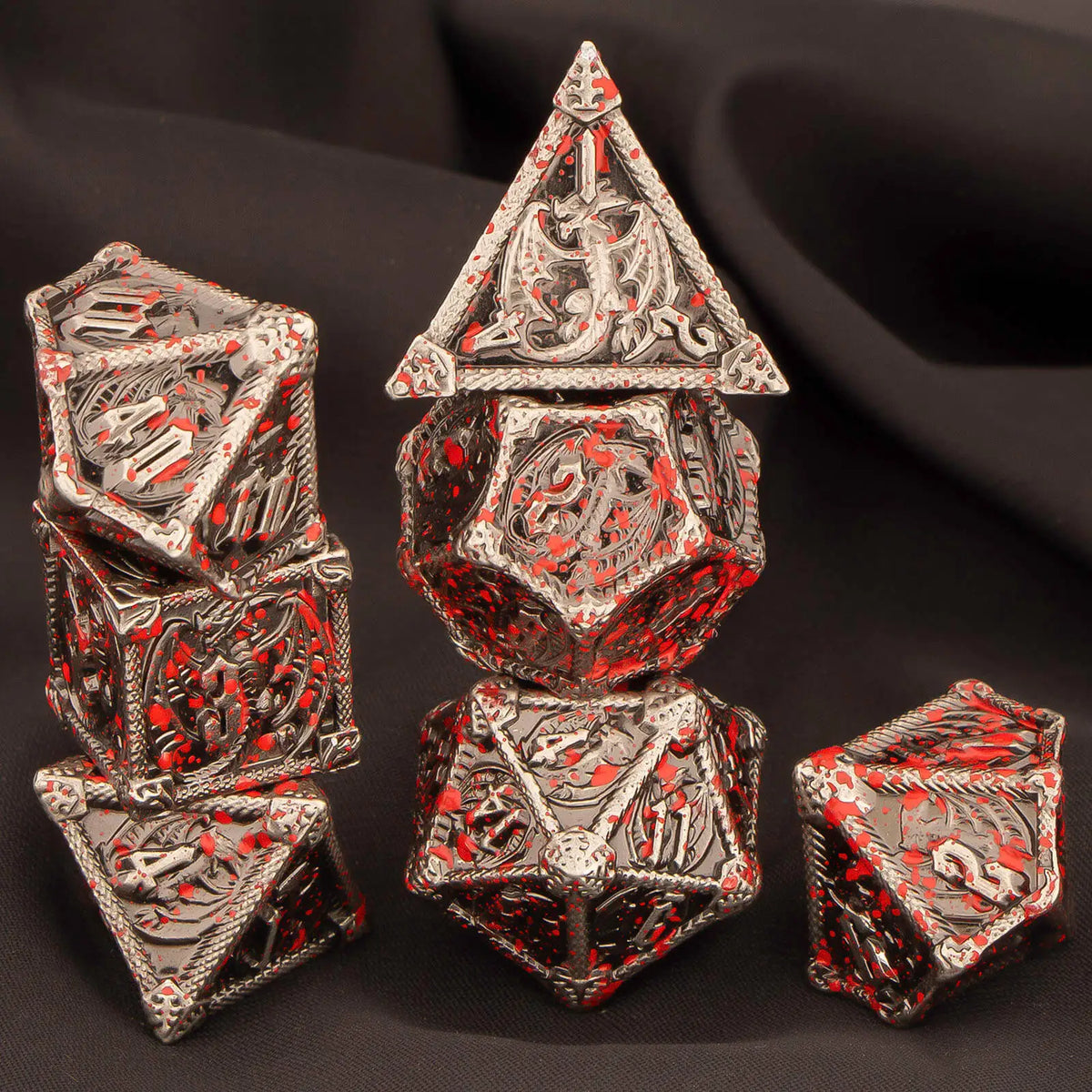 A set of seven premium metal polyhedral dice for tabletop gaming, featuring intricate red and silver detailing.